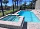 Beautiful screened-in pool and spa with brick surround and view of lush landscaping at 16446 Slate Pl, Bradenton, FL 34211