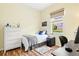 Bright bedroom features a twin bed, white dresser, wood flooring, and a sunny window view at 7453 Featherstone Blvd, Sarasota, FL 34238