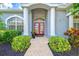 Charming front entrance featuring a brick walkway, columns, and red double doors at 7453 Featherstone Blvd, Sarasota, FL 34238