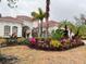 Stunning home exterior featuring vibrant tropical landscaping, palm trees, and a classic red tile roof at 14721 Bowfin Ter, Lakewood Ranch, FL 34202