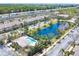 Community aerial view featuring a pool, pond, landscaping, townhome exteriors, and highway in the background at 1605 Napoli W Dr, Sarasota, FL 34232