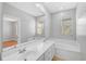 Bright bathroom featuring dual sinks, a large mirror, and a soaking tub near the window at 1605 Napoli W Dr, Sarasota, FL 34232