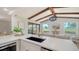 Close-up of modern kitchen featuring white countertops, gold fixtures, and views to the outdoor area and living area at 4118 Southwell Way, Sarasota, FL 34241