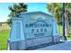 Entrance sign for Rothenbach Park with stone base and blue signage surrounded by green vegetation at 4118 Southwell Way, Sarasota, FL 34241