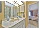 Bathroom vanity with white countertop, white cabinets, and flamingo shower curtain at 535 Spring Lakes Blvd, Bradenton, FL 34210
