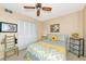 Bedroom featuring a ceiling fan, patterned bedding, and a view of palm tree artwork at 535 Spring Lakes Blvd, Bradenton, FL 34210