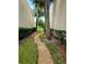 Exterior shot of a stone path between palm trees, grass, and hedges at 535 Spring Lakes Blvd, Bradenton, FL 34210