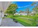 Manicured backyard featuring a stone patio, a verdant lawn and mature trees under a sunny blue sky at 9413 Andover Cir, Bradenton, FL 34210