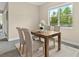 Cozy dining area features a wooden table, four chairs, neutral decor, and natural light from the window at 12029 Perennial Pl, Lakewood Ranch, FL 34211