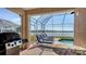 This screened-in patio features a view of the water, a grill, and cushioned lounge chairs for relaxing at 6920 74Th Street E Cir, Bradenton, FL 34203