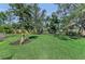 Well-maintained backyard with a large grassy area, mature trees, and wooden supports for swings at 7820 Seville Cir, Bradenton, FL 34209