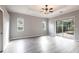 Large bedroom with gray floors, slider to patio, ceiling fan, and natural light from two windows at 2111 152Nd E Ct, Bradenton, FL 34212
