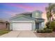 Two-story home featuring a two-car garage, lovely landscaping, and a welcoming front porch with a calming sky backdrop at 2347 Richwood Pike Dr, Ruskin, FL 33570