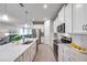 Open kitchen with stainless steel appliances, white cabinets, and granite countertops overlooking living room at 3747 Laughing Dove Ave, Sun City Center, FL 33573