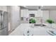 Well-lit kitchen showcasing white cabinets, stainless steel appliances, and a sleek island with stone countertops at 3747 Laughing Dove Ave, Sun City Center, FL 33573