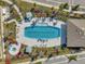Aerial view of a large community pool, surrounded by lounge chairs, landscaping, and a nearby recreation building at 3747 Laughing Dove Ave, Sun City Center, FL 33573