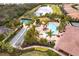 Aerial view of the community featuring a pool, tennis courts, and bocce ball surrounded by lush, mature landscaping at 5814 Cavano Dr, Sarasota, FL 34231