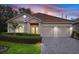 Charming single-story home with a well-manicured lawn, brick driveway and tile roof at sunset at 6211 Skyward Ct, Bradenton, FL 34203