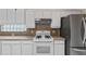 Close-up of a kitchen with white cabinets, stove, tile backsplash, and a refrigerator at 6211 Skyward Ct, Bradenton, FL 34203