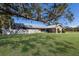 A home with a metal roof and stone accents is surrounded by a green lawn and shaded by a grand oak tree at 6615 13Th E Ave, Bradenton, FL 34208