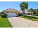 A well-maintained house featuring a pristine lawn, long driveway, and lush green landscaping at 1364 Berkshire Ct, Venice, FL 34292