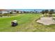 Aerial view of a community golf course with residences, a golf cart and a sand trap at 1364 Berkshire Ct, Venice, FL 34292
