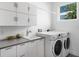 Well-organized laundry room with washer, dryer, cabinets, sink, and bright window at 2254 Hawthorne St, Sarasota, FL 34239
