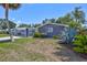 Inviting front yard showcasing lush greenery, a charming blue home exterior, and a convenient attached carport at 2321 Terry Ln, Sarasota, FL 34231