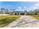 Well-manicured front yard and gray paved drive leading to a modern home with a two-car garage at 3598 Trinity St, North Port, FL 34291