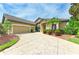 A beautiful tan-colored home with a three-car garage, lush landscaping, and a patterned driveway at 5304 96Th E St, Bradenton, FL 34211