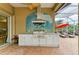 This outdoor kitchen boasts a stainless steel grill, custom tile art, and a view of the screened-in pool at 5304 96Th E St, Bradenton, FL 34211