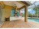 Covered outdoor kitchen features a grill, mosaic backsplash, and ample counter space near the screened pool at 5304 96Th E St, Bradenton, FL 34211