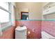 A bathroom featuring pink wall tiles with a white sink and toilet, plus a small cabinet on the wall at 5808 13Th Street E Ct, Bradenton, FL 34203