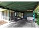 A carport with an enclosed sunroom area and storage shed, plus concrete flooring and wooden beams at 5808 13Th Street E Ct, Bradenton, FL 34203