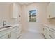 Well-lit laundry room boasts custom cabinets, granite countertops, stainless steel sink, and a window with natural light at 656 Tropical Cir, Sarasota, FL 34242
