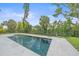 The backyard is equipped with a modern pool, surrounded by lush landscaping and privacy fencing at 656 Tropical Cir, Sarasota, FL 34242