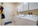 Well-equipped laundry room with washer, dryer, utility sink, cabinets, and exterior access at 92 Tall Trees Ct, Sarasota, FL 34232