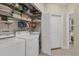 Bright laundry room with washer, dryer, storage shelves, and view to bedroom at 1359 Tearose Pl, Sarasota, FL 34239
