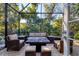 Relax in this screened-in patio with comfortable seating, offering a private outdoor space surrounded by lush greenery at 1359 Tearose Pl, Sarasota, FL 34239