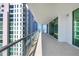 A long, covered balcony with a tile floor and glass railing offers stunning views of the surrounding buildings at 301 Quay Commons # 1411, Sarasota, FL 34236