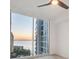 Bedroom with a large window framing beautiful views of the bay and city buildings at sunset at 301 Quay Commons # 1411, Sarasota, FL 34236