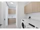 Well-lit laundry room featuring a washer, dryer, and wooden cabinets above at 301 Quay Commons # 1411, Sarasota, FL 34236