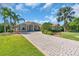 Charming home with a paver driveway, mature trees, and lush landscaping at 3336 Lakeside Cir, Parrish, FL 34219