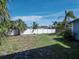 A spacious fenced backyard with a mix of grass and open space, complemented by lush palm trees and blue skies at 651 Fox St, Longboat Key, FL 34228