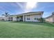 Expansive backyard with lush lawn, tropical plants, and covered patio at 17915 Palmiste Dr, Bradenton, FL 34202