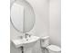 Bathroom featuring pedestal sink, toilet and large round mirror at 17915 Palmiste Dr, Bradenton, FL 34202
