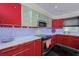 Modern kitchen featuring sleek, red cabinetry, stainless steel appliances, and bright white countertops at 4147 Augustine Ave, Sarasota, FL 34231