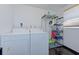 Bright laundry room featuring a white washer and dryer set with shelving unit and black tile flooring at 4147 Augustine Ave, Sarasota, FL 34231