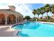 A bright blue community pool with stairs leading into the water and palm trees on a sunny day with a blue sky at 4244 Reflections Pkwy, Sarasota, FL 34233
