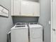 This laundry room has a washer and dryer and white cabinets for storage at 7812 Birdie Bend Way, Sarasota, FL 34241